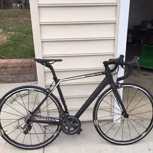 black and white road bicycle leaning against a beige garage wall
